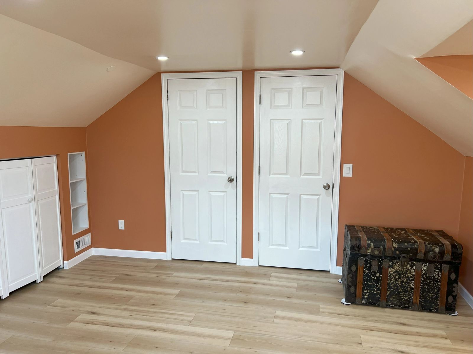 Finished bonus room with white built-in cabinets and drawers, vinyl plank flooring and a wall-mounted television