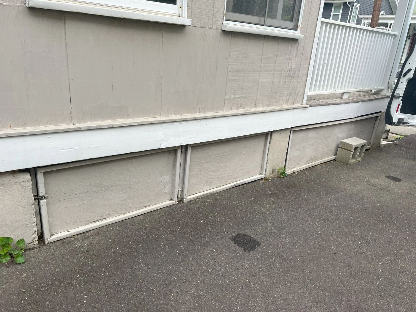 Before: bare unfinished crawlspace skirting panels along the side of a house