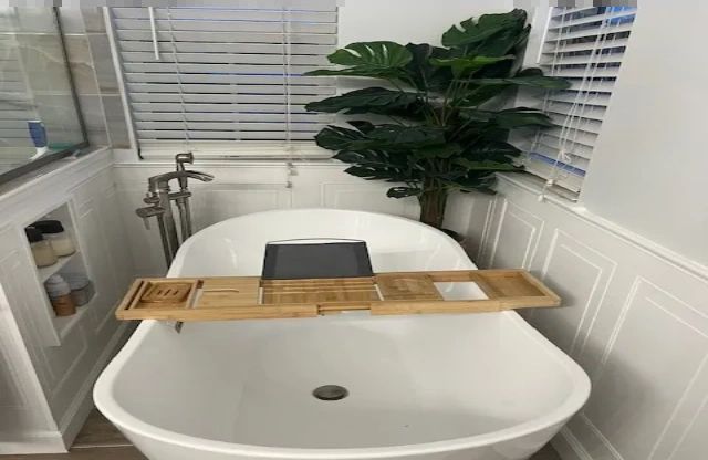 Freestanding soaking tub with floor-mounted filler against white wainscot panelling